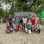 Happy tour group at the Manuel Antonio National Park entrance sign with their Wakoo Tours guide
