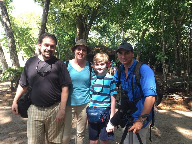 Jason with a family of three, binoculars around his neck, at the end of a guided tour in Manuel Antonio National Park