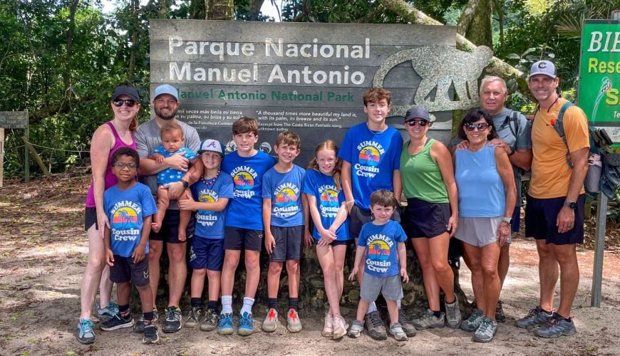 Family with young children at the Manuel Antonio National Park sign on a Wakoo Tours guided tour