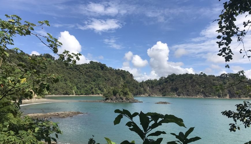 View over a turquoise bay and forested headland from a trail lookout in Manuel Antonio National Park
