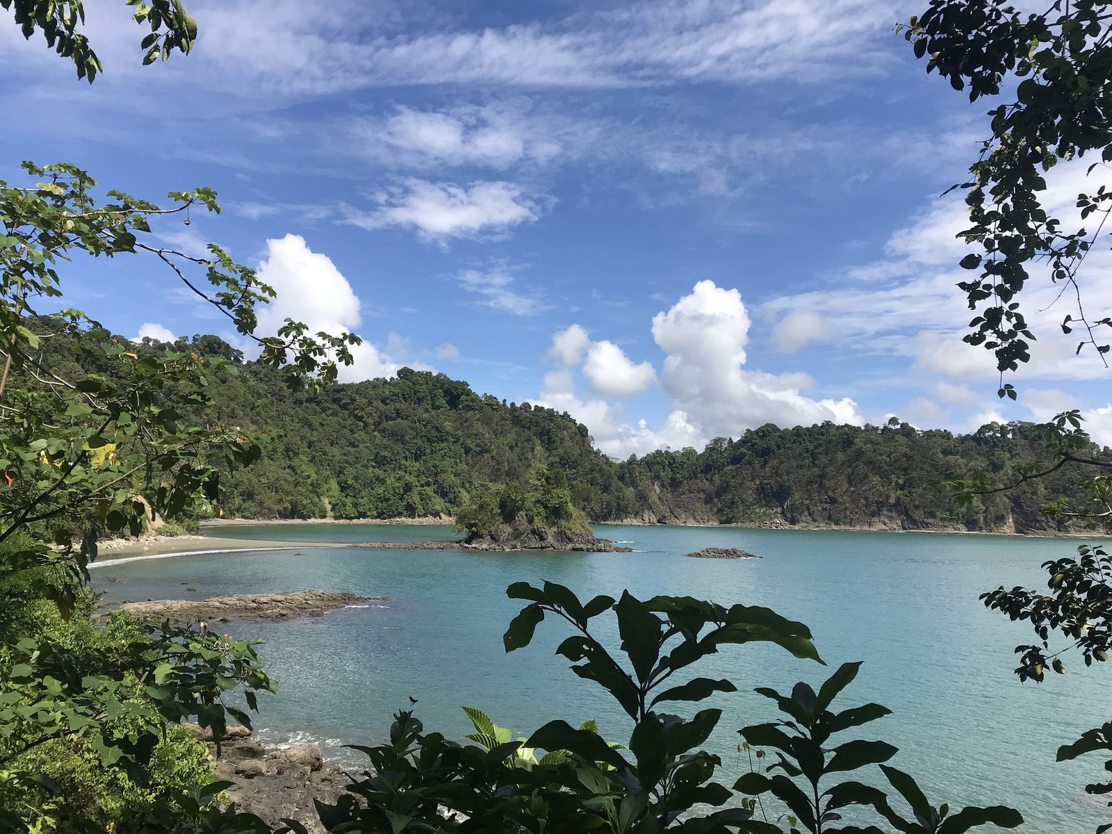 View over a turquoise bay and forested headland from a trail lookout in Manuel Antonio National Park