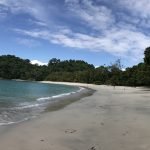 Panoramic view of a curving white sand beach in Manuel Antonio National Park with turquoise water