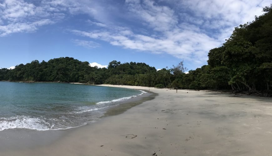 Panoramic view of a curving white sand beach in Manuel Antonio National Park with turquoise water
