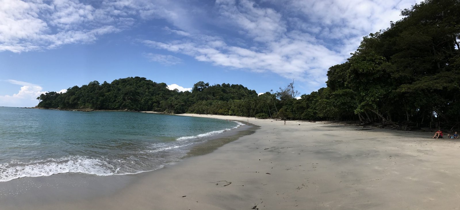 Panoramic view of a curving white sand beach in Manuel Antonio National Park with turquoise water