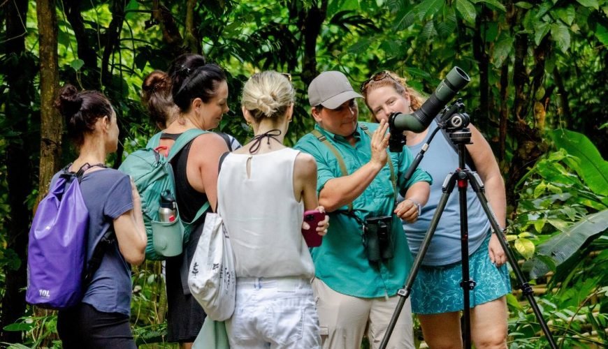 Wakoo Tours naturalist guide explaining a wildlife sighting to guests around a spotting scope in Manuel Antonio National Park