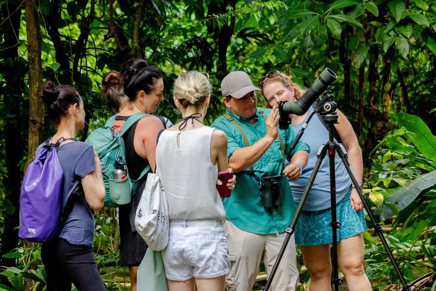 Wakoo Tours naturalist guide explaining a wildlife sighting to guests around a spotting scope in Manuel Antonio National Park