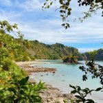 Puerto Escondido beach, rocky shoreline and rainforest in Manuel Antonio National Park